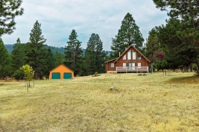 view of yard featuring a wooden deck, an outbuilding, a forest view, and a garage