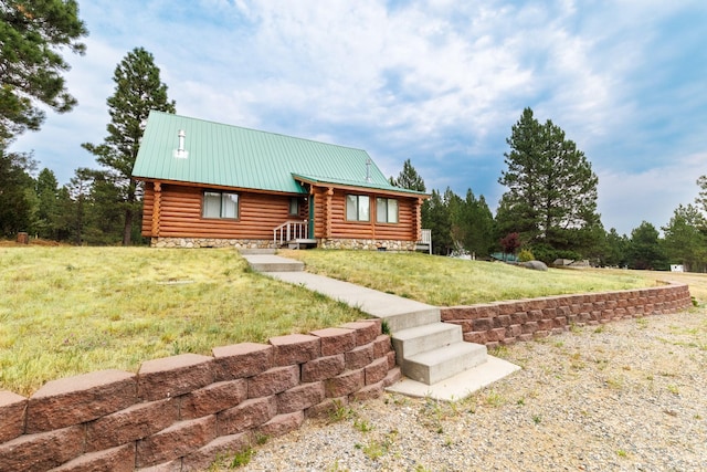 log-style house with log siding, a front yard, and metal roof
