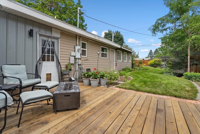 wooden terrace featuring a lawn and a fire pit