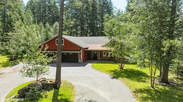 view of front of house featuring a front yard, covered porch, driveway, and an attached garage