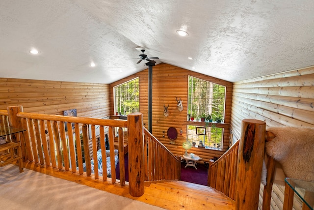 stairs featuring rustic walls, a textured ceiling, carpet flooring, and lofted ceiling