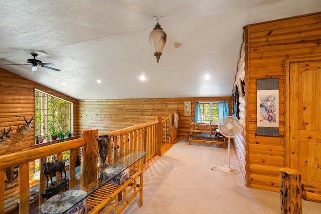 interior space with rustic walls, a textured ceiling, vaulted ceiling, and light colored carpet