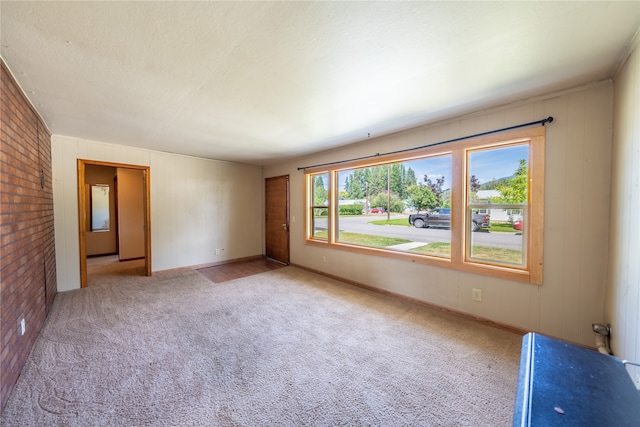 unfurnished room with light carpet and brick wall