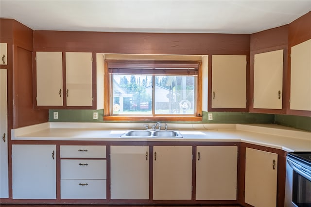 kitchen with sink, stove, and white cabinetry