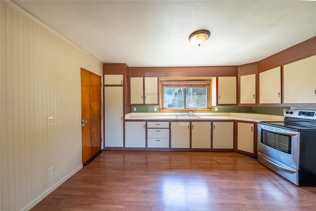 kitchen with electric range, sink, cream cabinets, and hardwood / wood-style flooring