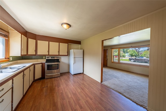 kitchen featuring cream cabinets, light carpet, sink, white fridge, and electric range