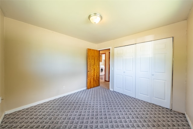 unfurnished bedroom featuring washer / clothes dryer, carpet flooring, and a closet