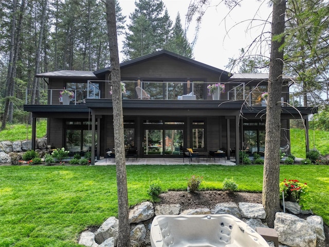 rear view of house featuring a patio, a yard, and a balcony