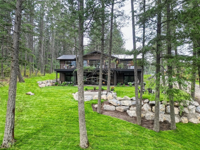 rear view of house featuring metal roof, a lawn, a wooden deck, and a standing seam roof