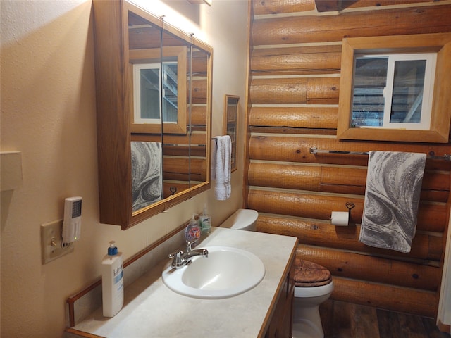 bathroom with log walls, vanity, toilet, and wood-type flooring