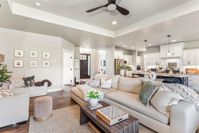 living room featuring sink, ceiling fan, hardwood / wood-style floors, and a raised ceiling