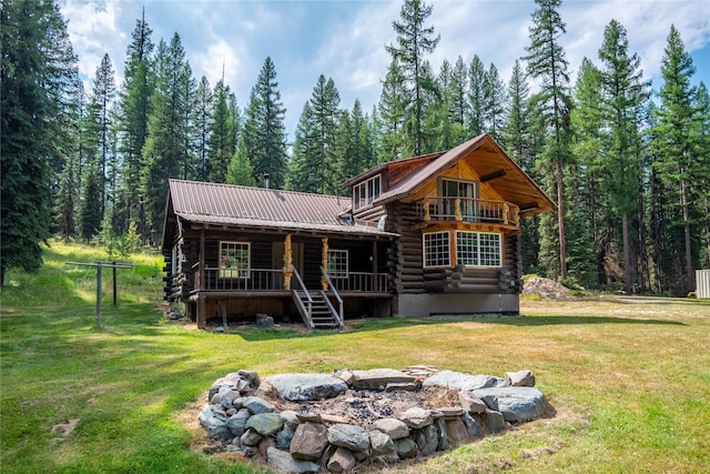 view of front facade featuring metal roof, log exterior, an outdoor fire pit, and a front yard