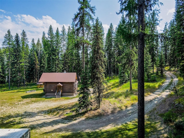 exterior space featuring entry steps, metal roof, log exterior, and a forest view