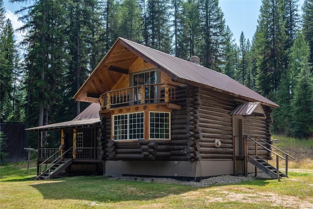 view of front of property with metal roof, log exterior, a front lawn, and a balcony