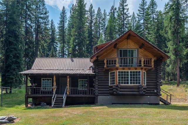 view of front of home with a porch, log exterior, and a front lawn