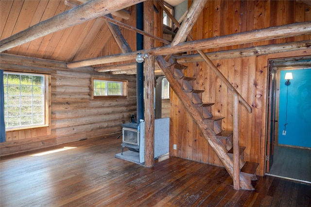 unfurnished living room with a wood stove, wood-type flooring, and beam ceiling