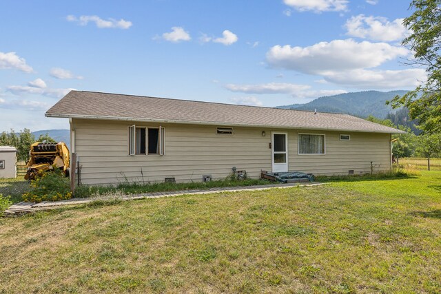 rear view of house with a lawn and a mountain view