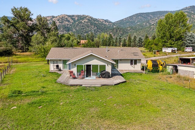 back of house with a deck with mountain view and a lawn