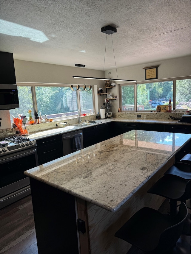 kitchen with black appliances, a wealth of natural light, dark hardwood / wood-style flooring, and a textured ceiling