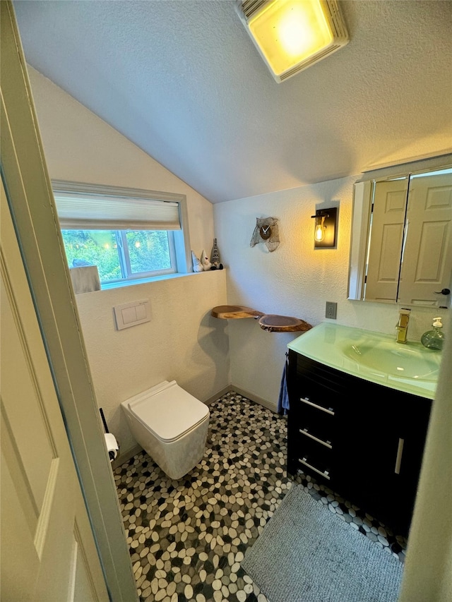 bathroom featuring vanity, lofted ceiling, tile patterned floors, and a textured ceiling