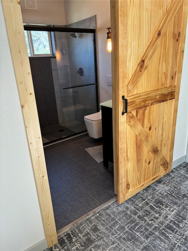 bathroom with vanity, toilet, and a shower with door