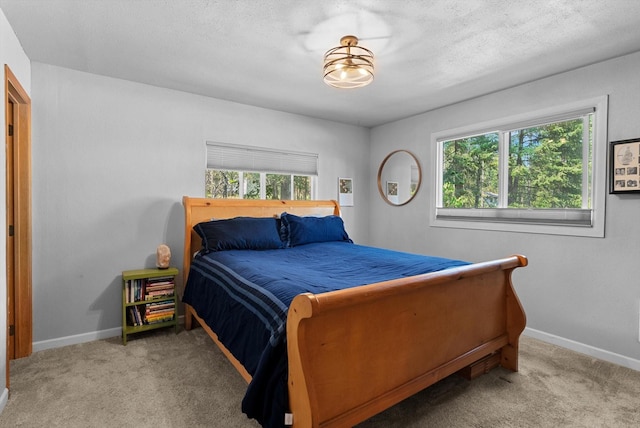 bedroom featuring light colored carpet, a textured ceiling, and baseboards