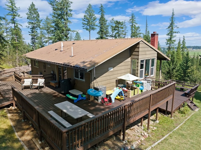 back of property featuring a chimney, metal roof, and a deck