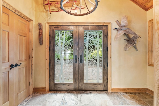 entryway with stone tile floors, french doors, and baseboards