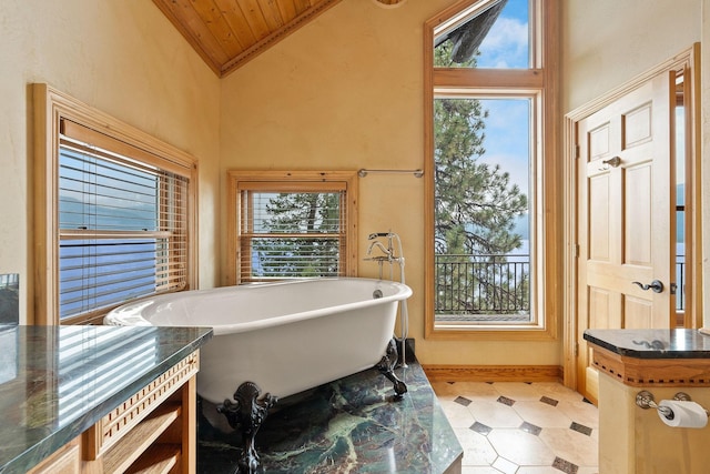 bathroom with tile patterned floors, lofted ceiling, a soaking tub, and a healthy amount of sunlight