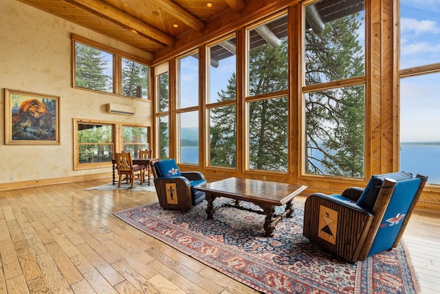 sunroom / solarium with beam ceiling, an AC wall unit, a water view, and wooden ceiling