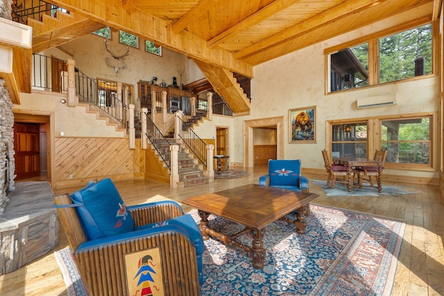 living room with stairway, beamed ceiling, a wall unit AC, and plenty of natural light