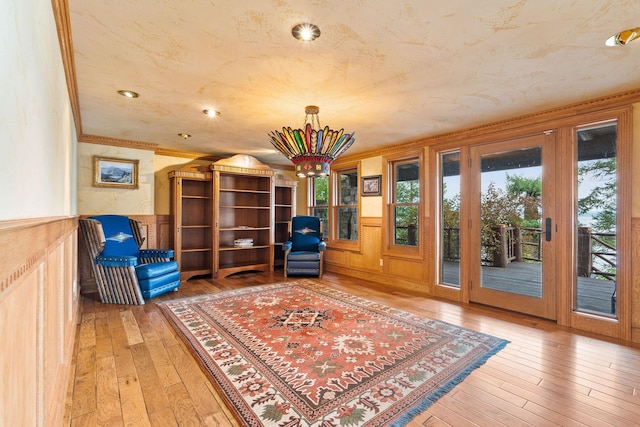 unfurnished room with wood-type flooring, a textured ceiling, wainscoting, and crown molding