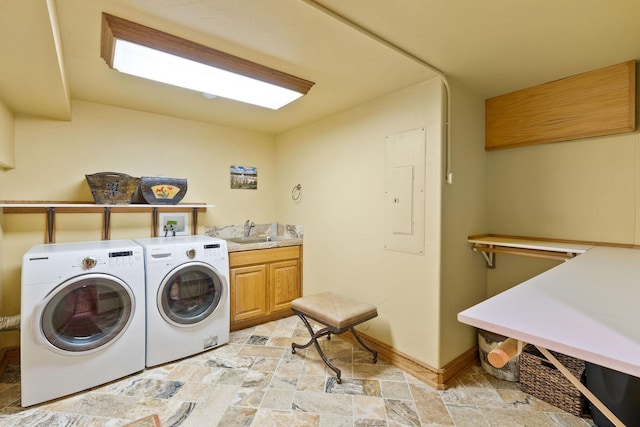 laundry room featuring a sink, stone finish flooring, washing machine and dryer, cabinet space, and baseboards