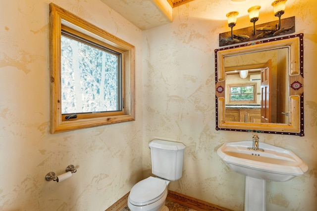 bathroom with baseboards, toilet, and wallpapered walls