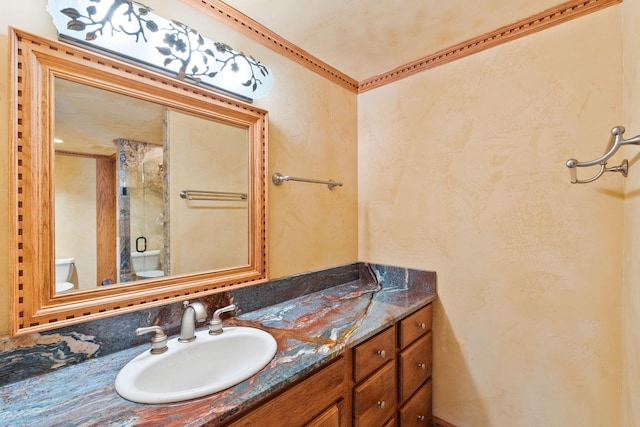 bathroom with toilet, vanity, and a shower with shower door