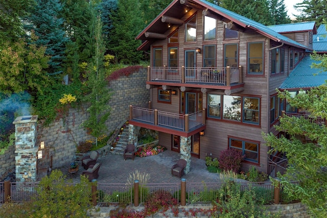 back of house featuring a balcony, metal roof, a patio, and fence