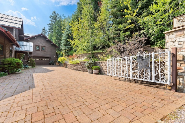 view of patio with decorative driveway, a garage, and fence