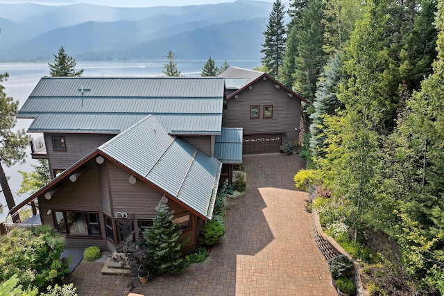 back of house with a water and mountain view, metal roof, decorative driveway, and a garage