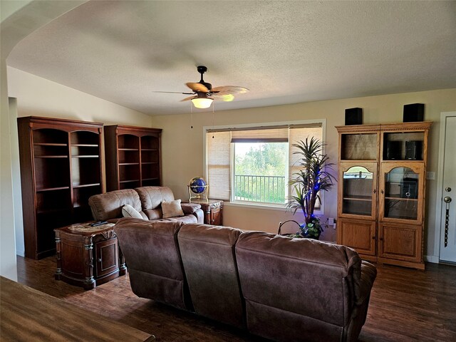 living room with a ceiling fan, dark wood-style flooring, and a textured ceiling