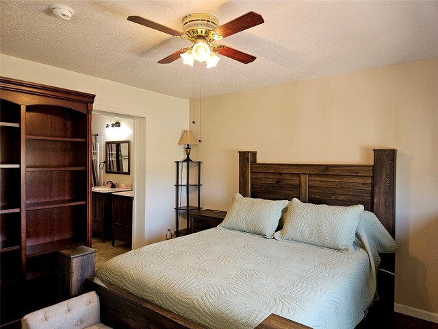 bedroom featuring ceiling fan, ensuite bathroom, and a textured ceiling