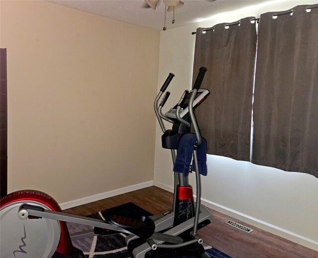 exercise room featuring visible vents, baseboards, and wood finished floors