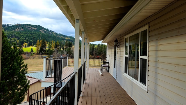 wooden terrace featuring a wooded view and a mountain view