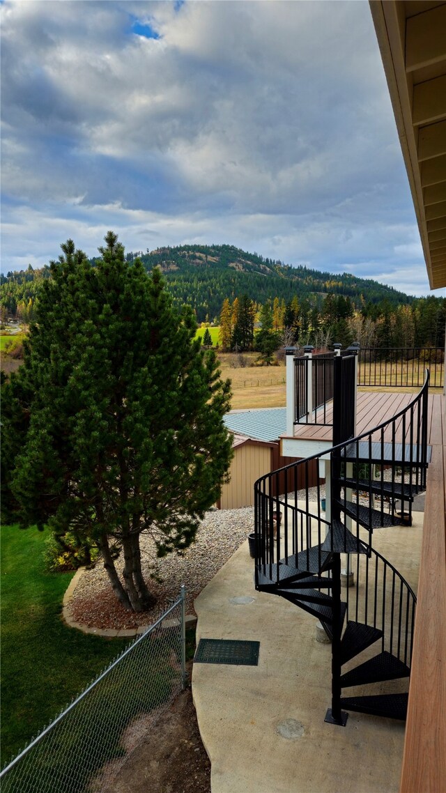 exterior space featuring a wooded view, a mountain view, and fence