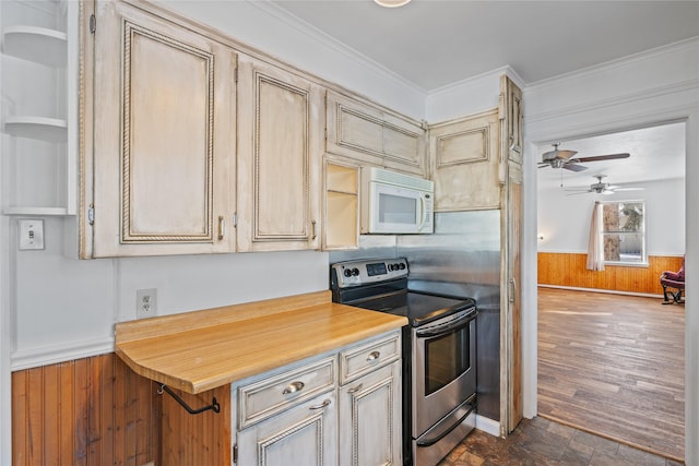 kitchen with stainless steel range with electric stovetop, ceiling fan, ornamental molding, and wooden walls