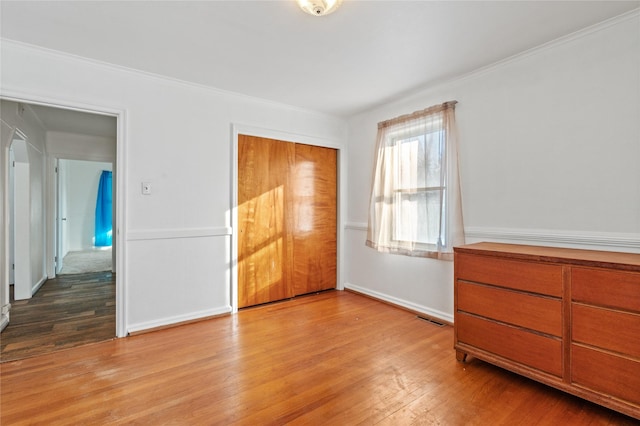 unfurnished bedroom with light hardwood / wood-style flooring, a closet, and ornamental molding