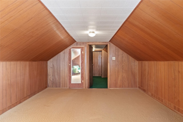 additional living space featuring wooden walls, carpet, and lofted ceiling