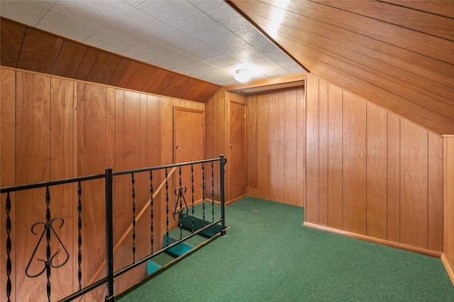 additional living space featuring vaulted ceiling, dark carpet, and wood walls