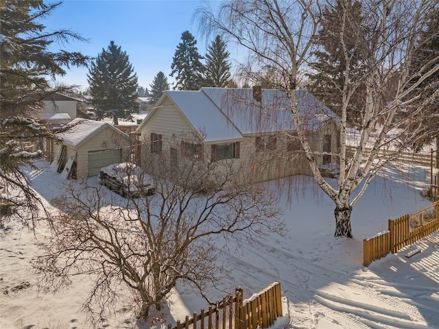 snow covered property featuring a garage and an outdoor structure