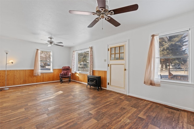 unfurnished room featuring a wood stove, ceiling fan, and hardwood / wood-style flooring