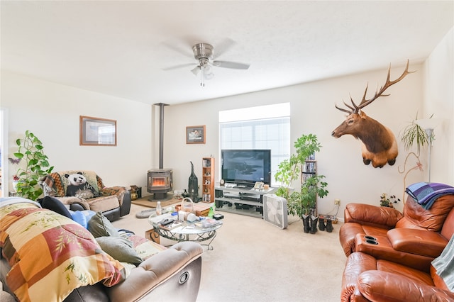 living room with ceiling fan, a wood stove, and carpet flooring